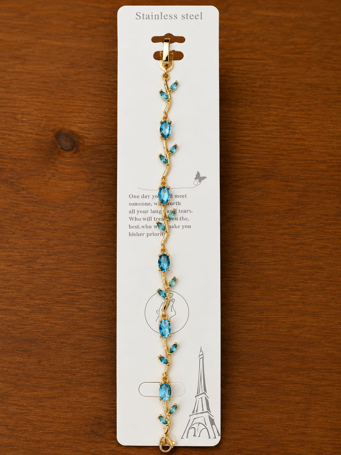 Blue Vine Bracelet in gold-tone style with blue leaf-shaped stations placed along a warm metallic vine
