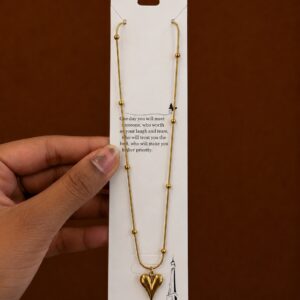 Gold-tone textured heart pendant necklace on a ball-station chain