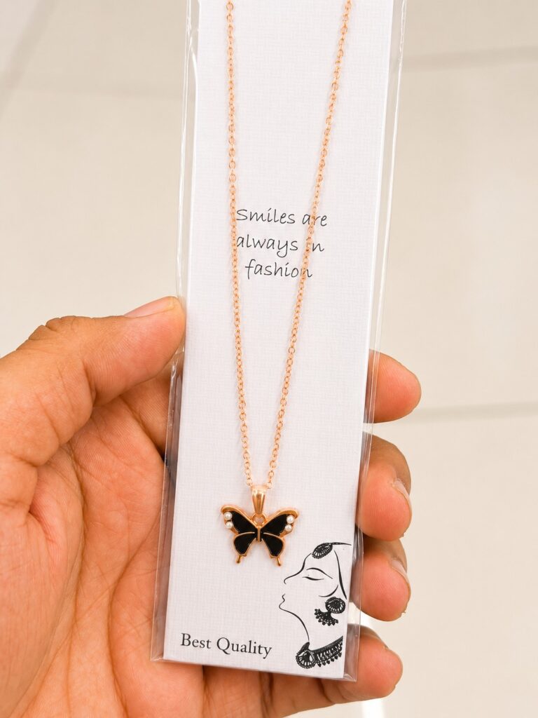 Rose gold-tone necklace with a black butterfly pendant and pearl-like accents
