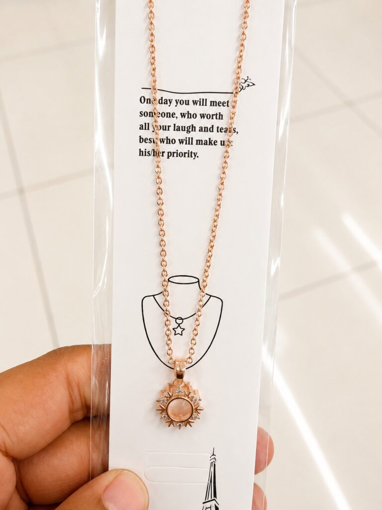 Rose gold-tone sun pendant necklace with a pink center and clear stones