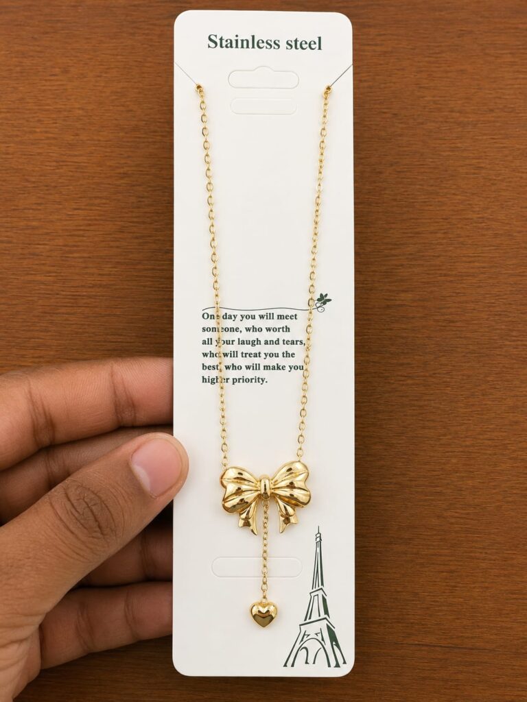 Gold-tone bow pendant necklace with a dangling heart